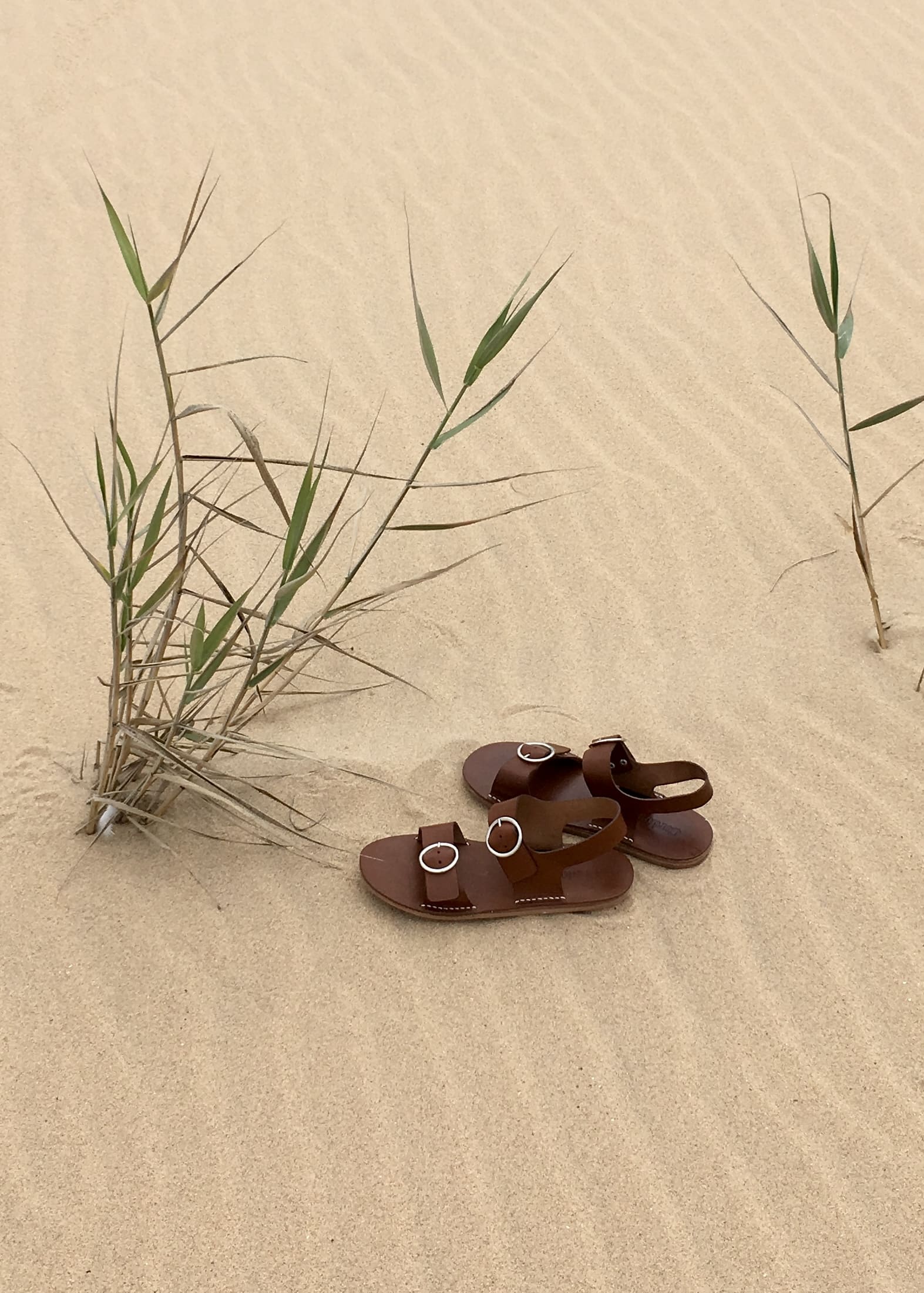 Sandálias Líli sobre a areia, na praia